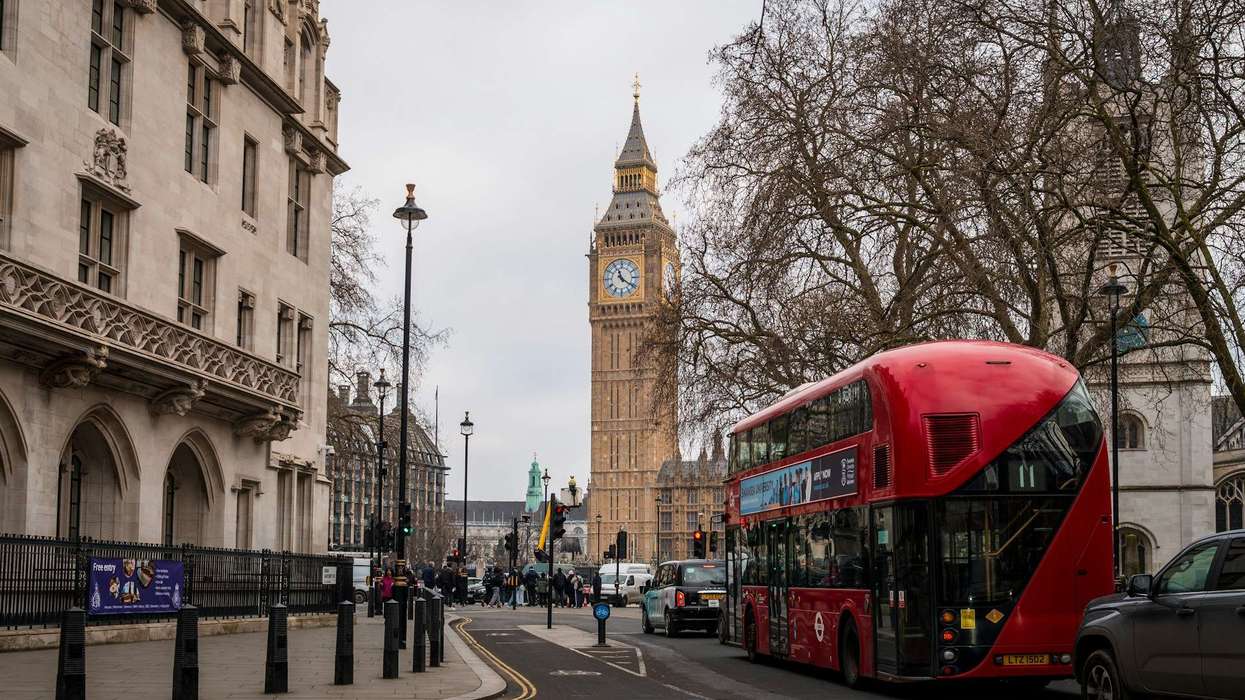 A red double-decker bus passes Big Ben in Westminster, a busy central London scene relevant to questions about London safety in 2026