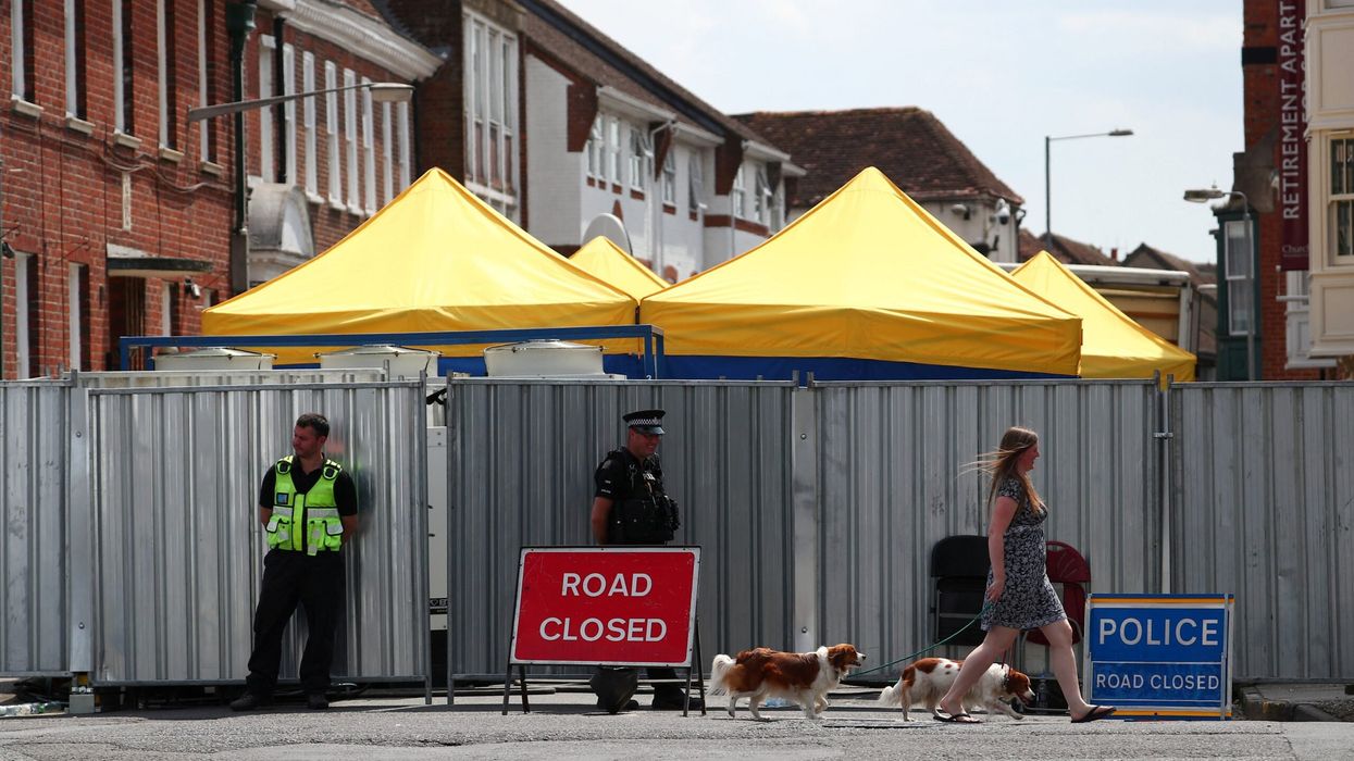 A woman walks her dogs past police officers stationed outside barriers blocking the street where Dawn Sturgess lived before dying after being exposed to a Novichok nerve agent, in Salisbury, July 19, 2018. (Photo: Reuters)