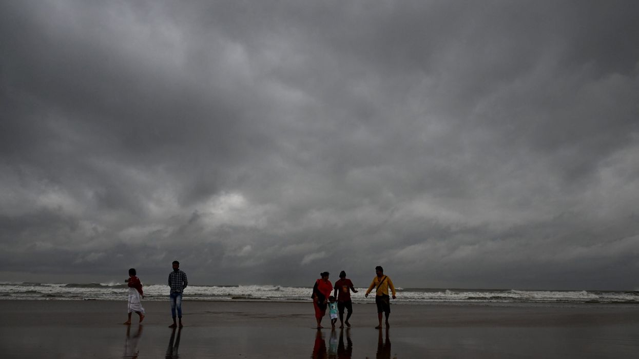 Dark clouds loom over the sea as local people and tourists walk along a beach in Digha, around 200km southwest of Kolkata, on October 24, 2024, as cyclone Dana is likely to hit the coasts of India's West Bengal and Odisha states. (Photo: Getty Images)