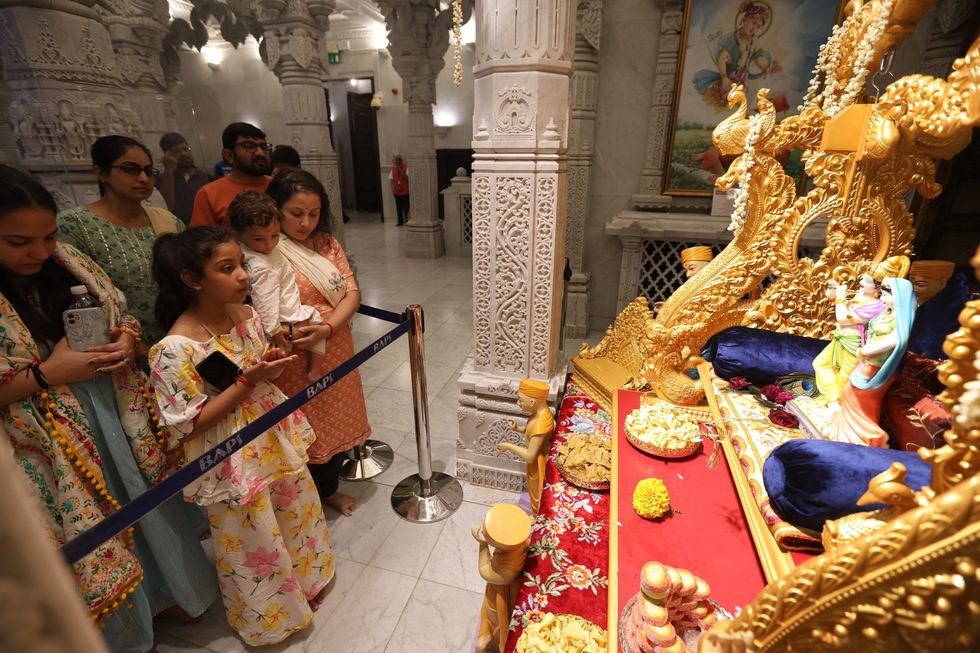 Devotees offering prayers and cradling the murti of Shri Krishna Bhagwan on a decorated swing