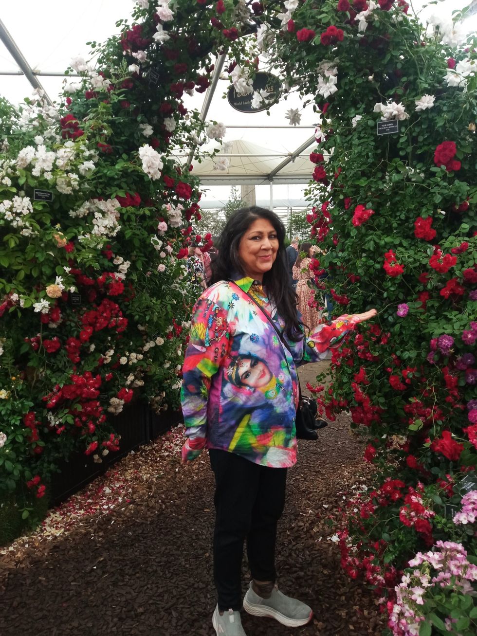 p17 LEAD Inset 4 Chila Burman at Chelsea. Admiring red roses 26 May 2024