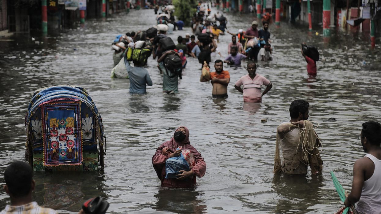People wades past flooded water in Feni, Chittagong, Bangladesh, on August 24. (Photo: Getty Images)