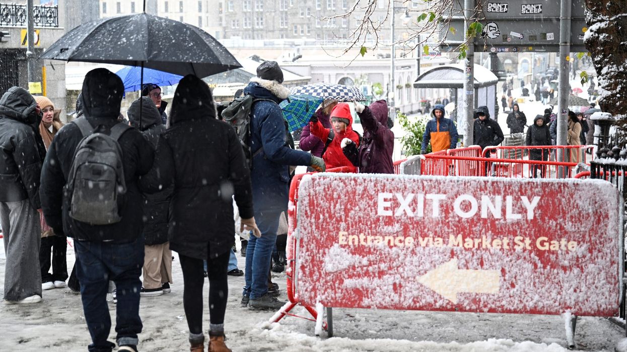 People wait in the snow for the Christmas Market to open during Storm Bert, along Princes Street in Edinburgh. (Photo: Reuters)