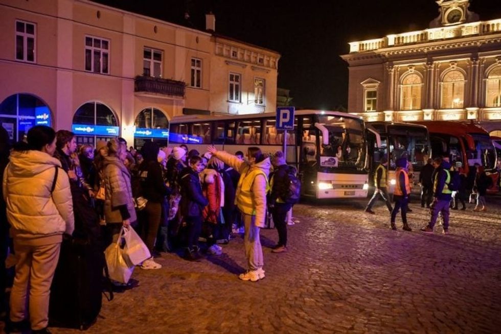 People wait to board buses taking them to Warsaw outside the train station in Przemysl, which became the main hub for transportation of refugees fleeing war in Ukraine on March 12, 2022.