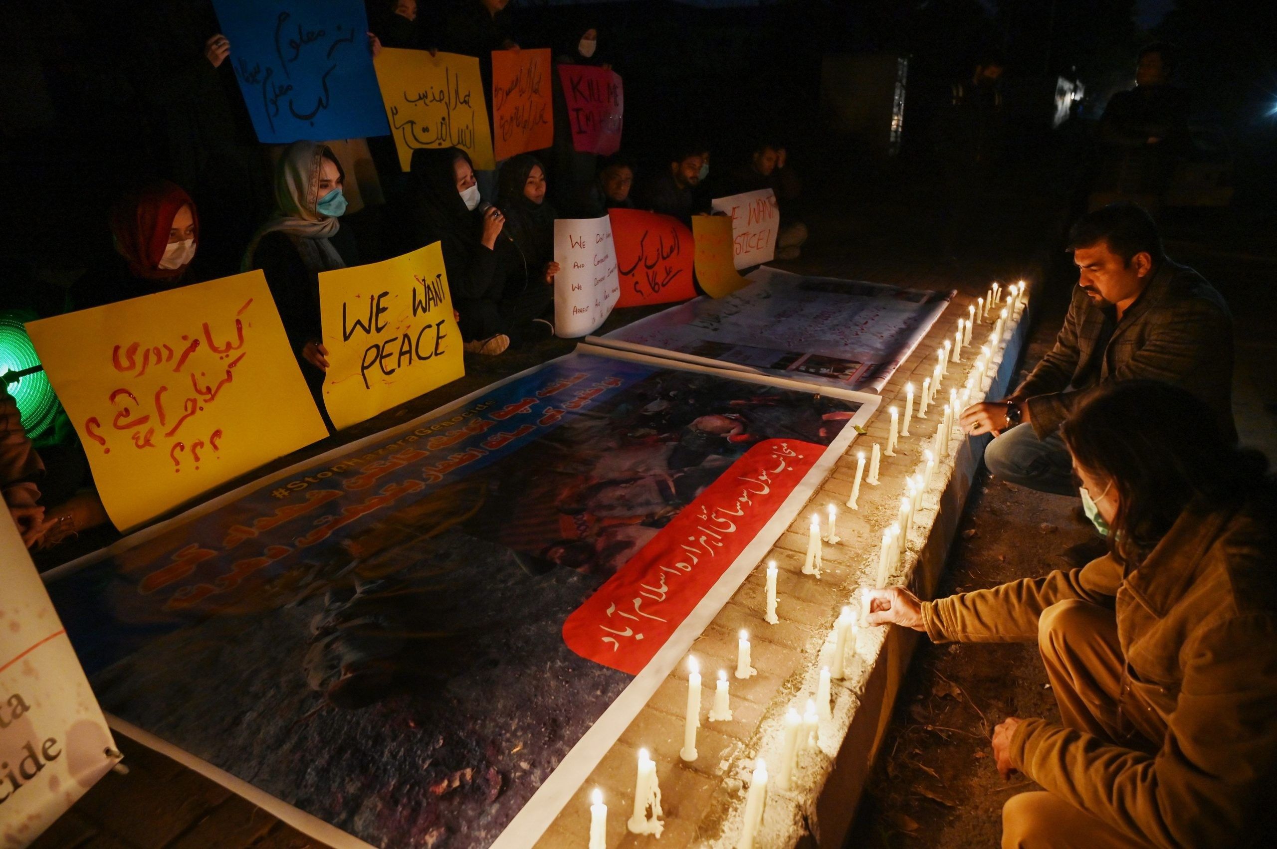 Demonstrators from Shiite Hazara community carry placards beside candles to pay tribute to miners who were killed in an attack by gunmen in the mountainous Machh area, during a vigil in Islamabad on January 6, 2021. (Photo by Aamir QURESHI / AFP)