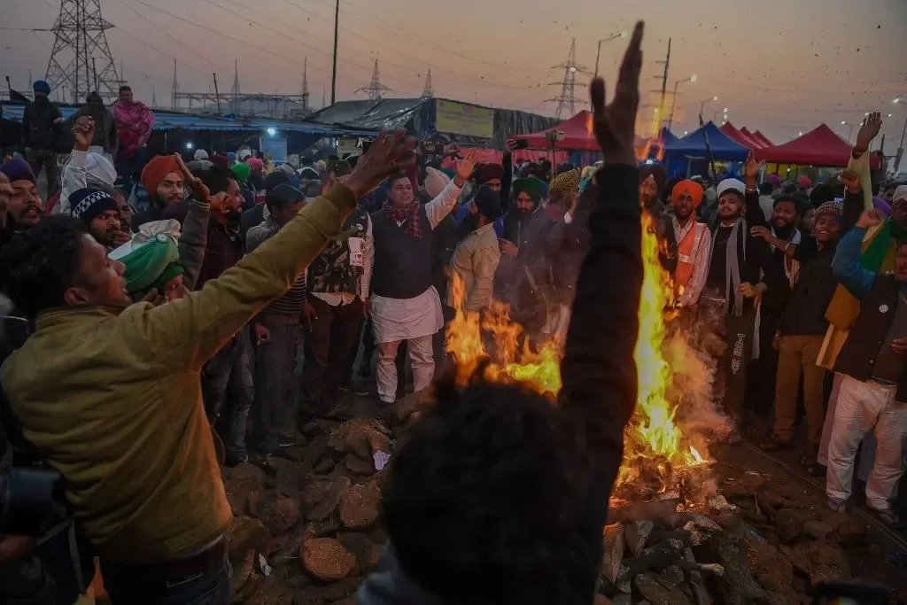 Protesting farmers shout slogans after burning copies of recent agricultural reforms bill while celebrating Lohri festival, as they continue to protest along a blocked highway against the central government, at the Gazipur Delhi-Uttar Pradesh state border, in Ghaziabad on January 13, 2021. (Photo by PRAKASH SINGH/AFP via Getty Images)
