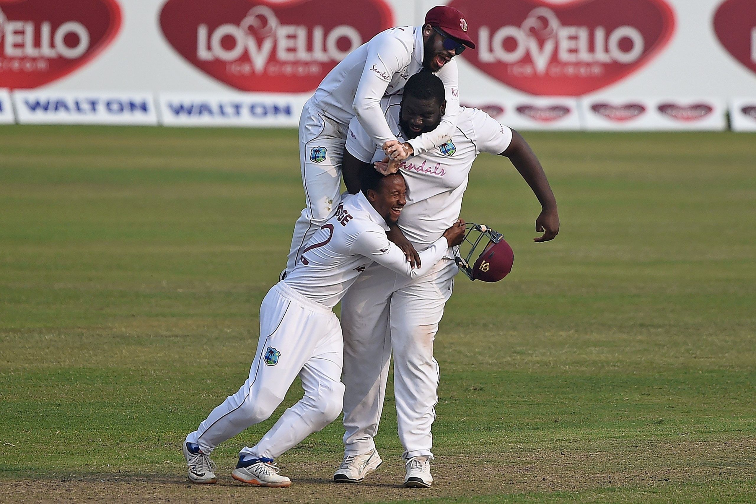 West Indies' John Campbell (top) with teammates Rahkeem Cornwall (R) and Shayne Moseley celebrate the dismissal of Bangladesh's Liton Das (not pictured) during the fourth day of the second Test cricket match between West Indies and Bangladesh at the Sher-e-Bangla National Cricket Stadium in Dhaka in February 14, 2021. (Photo by Munir Uz zaman / AFP) (Photo by MUNIR UZ ZAMAN/AFP via Getty Images)