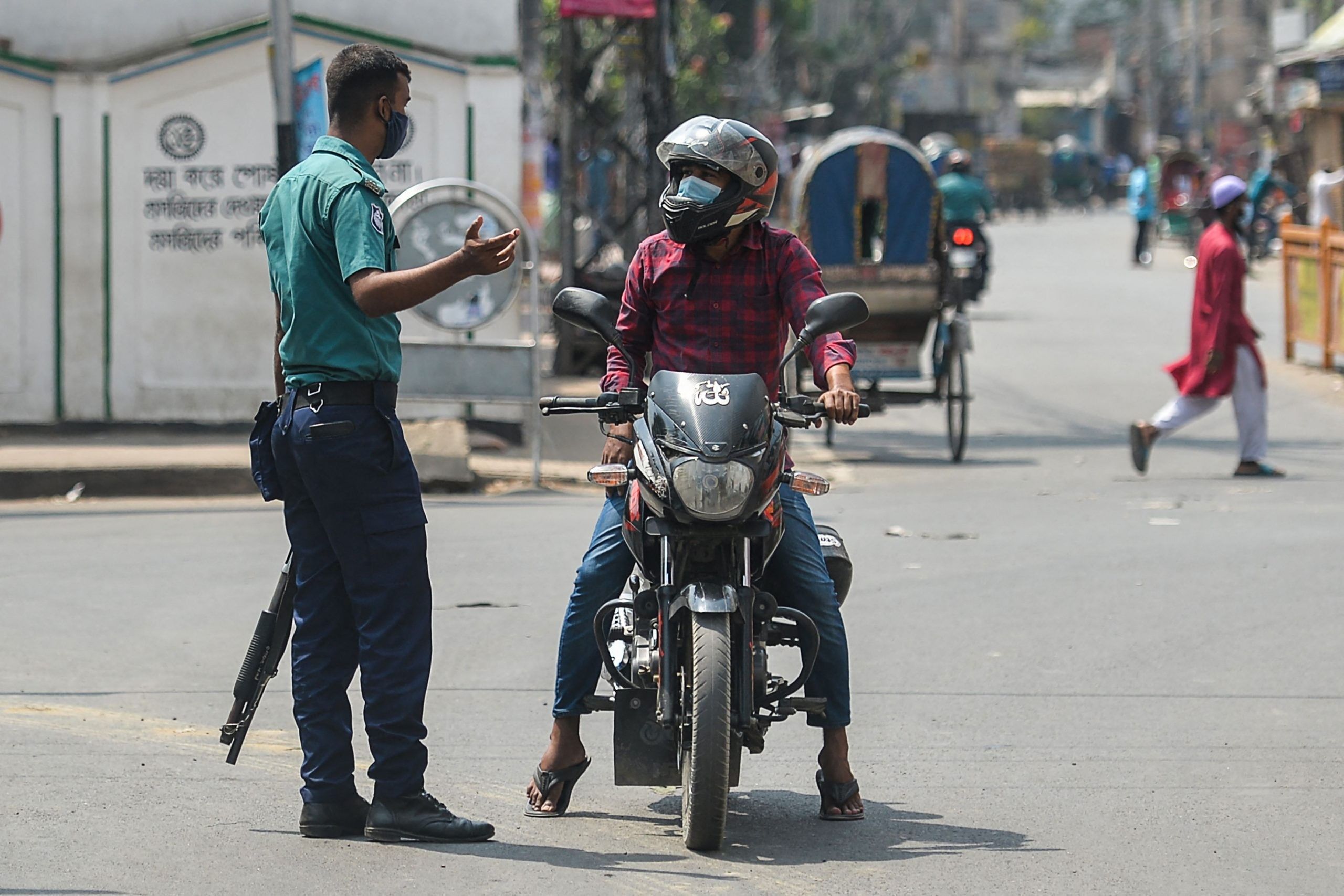 A policeman stops a motorist at a checkpoint as Bangladesh's authorities enforced a strict lockdown to combat the spread of the Covid-19 coronavirus, in Dhaka on April 14, 2021. (Photo by Munir uz zaman / AFP)