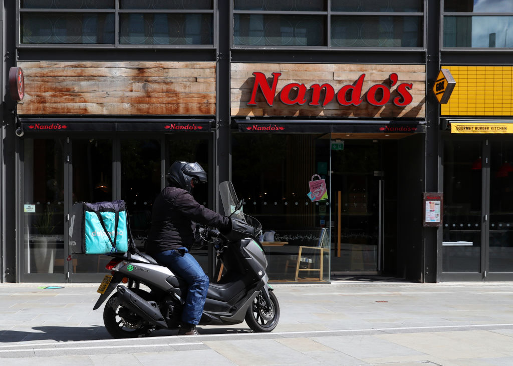 Deliveroo driver collects a takeaway order from Nando's in Aylesbury