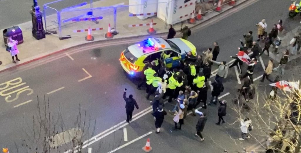 British Labour Party leader Keir Starmer gets into a police car as protesters surround him